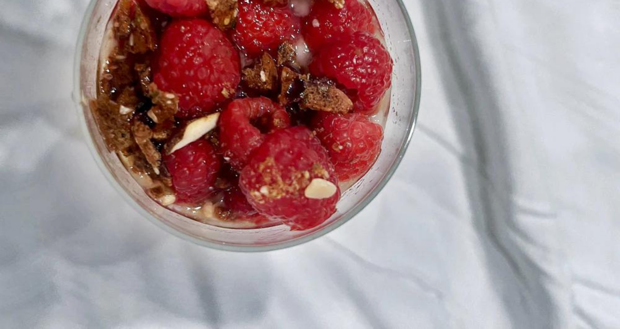 A gluten-free parfait with Cinnamon Maple Crisps, fresh berries, and dairy-free yogurt on a white sheet.